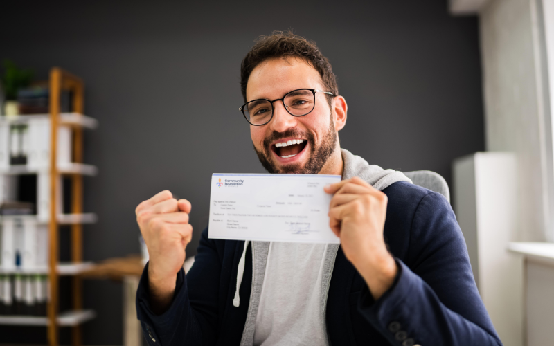 Pictured: A male-presenting nonprofit leader receiving their Sparking Change Mini-Grants check on behalf of their nonprofit.