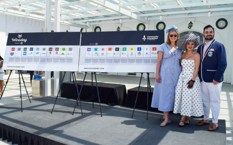two women and one man standing next to a sign showcasing the nonprofits selected for a prize.